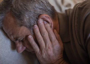 Elderly man holding his ear in pain, indicating symptoms of cholesteatoma