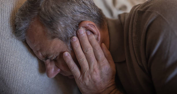 Elderly man holding his ear in pain, indicating symptoms of cholesteatoma
