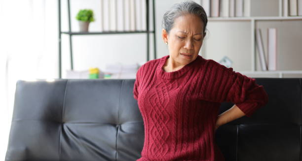 Elderly woman holding lower back in pain, showing symptoms of chronic kidney disease
