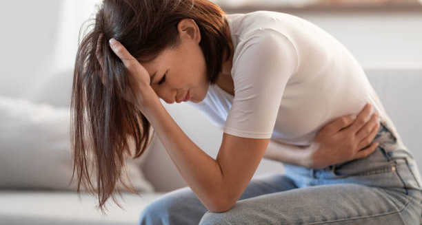 Woman clutching stomach and head in pain, showing symptoms of chronic pancreatitis.