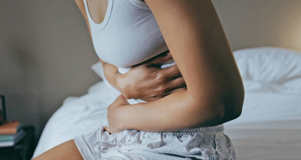 Woman clutching stomach in pain, a symptom of Clostridium difficile infection