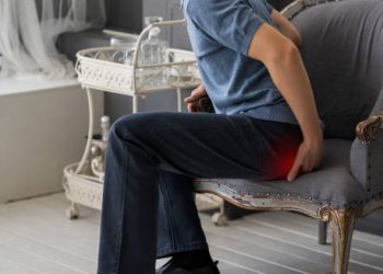 Man sitting on a chair experiencing coccyx pain