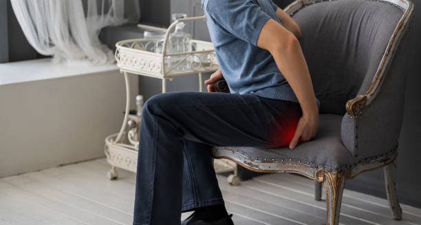 Man sitting on a chair experiencing coccyx pain