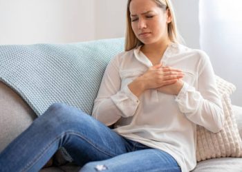 Woman holding chest in discomfort due to congenital heart disease symptoms