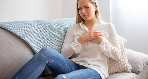 Woman holding chest in discomfort due to congenital heart disease symptoms