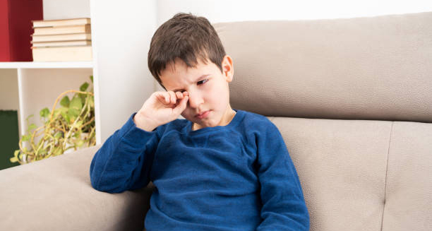 Child rubbing irritated eye showing early symptoms of conjunctivitis