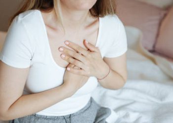 Woman clutching her chest in discomfort, showing a common symptom of coronary heart disease.