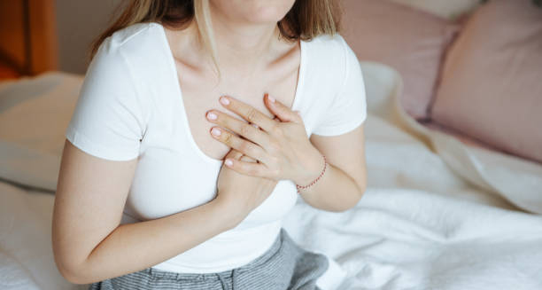 Woman clutching her chest in discomfort, showing a common symptom of coronary heart disease.