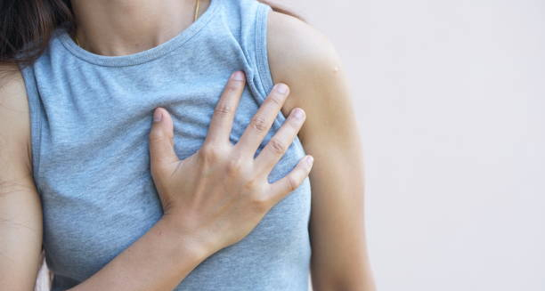 Woman holding her chest in discomfort, indicating pain typical of costochondritis.