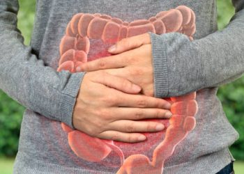 Person clutching abdomen with an overlay of the digestive tract, indicating pain and discomfort typical of Crohn’s disease symptoms.