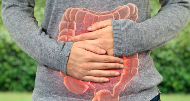 Person clutching abdomen with an overlay of the digestive tract, indicating pain and discomfort typical of Crohn’s disease symptoms.