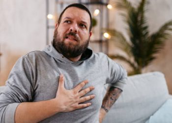 Man clutching his chest, showing signs of respiratory distress, a common symptom of cystic fibrosis.