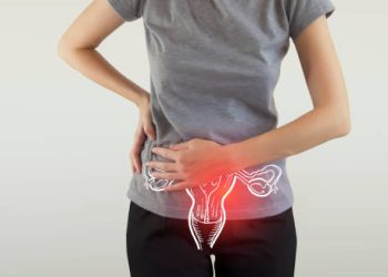 Woman holding her lower abdomen with an illustrated overlay of the bladder and uterus indicating pain.
