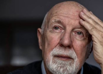 Elderly man holding his head, appearing confused or distressed