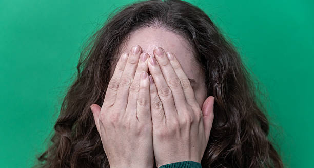 Woman covering her face with hands, showing signs of distress