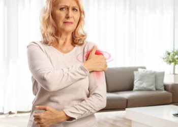 Middle-aged woman clutching painful shoulder with visible signs of dislocation