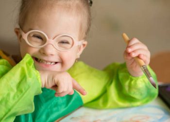 Smiling young girl with Down’s Syndrome painting with a brush
