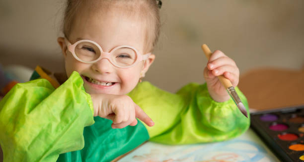 Smiling young girl with Down’s Syndrome painting with a brush
