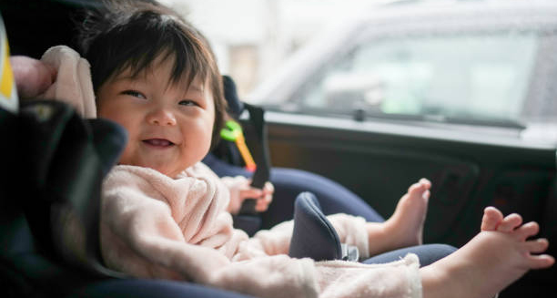 Smiling baby with short limbs sitting in a car seat