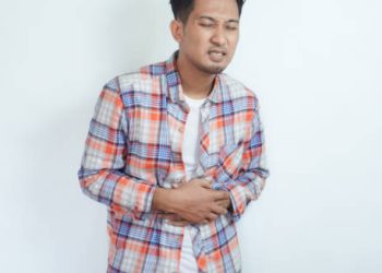 Man clutching his stomach in pain against a plain background