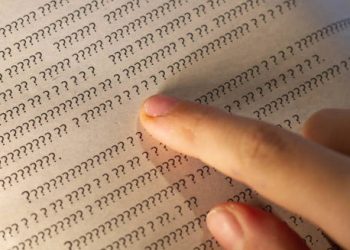 Finger pointing at unreadable question marks in a book, representing dyslexia