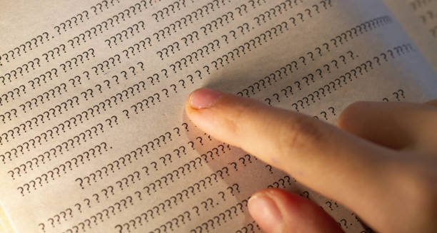 Finger pointing at unreadable question marks in a book, representing dyslexia