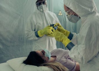 Healthcare workers in protective gear attending to a patient with suspected Ebola symptoms.