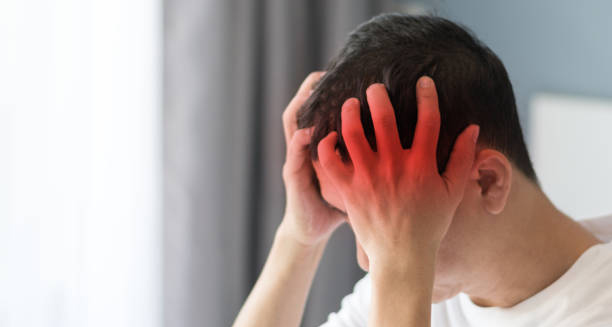 Man holding his head in pain with red highlight indicating headache from encephalitis.