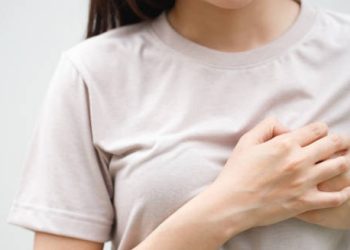 Woman clutching chest in discomfort, indicating possible symptoms of endocarditis.