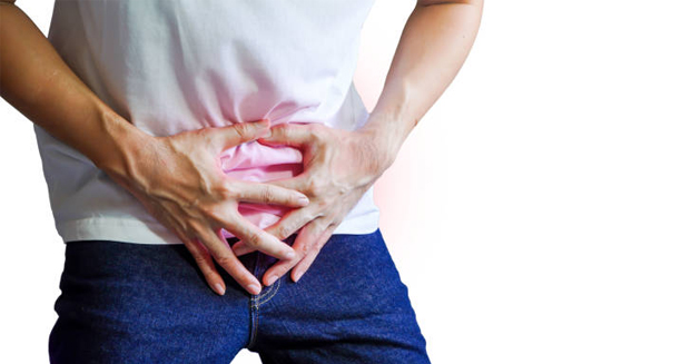 Man clutching lower abdomen in discomfort, indicating symptoms of enlarged prostate