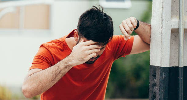 Man holding his head and leaning on a pole, experiencing dizziness and headache—symptoms of erythrocytosis