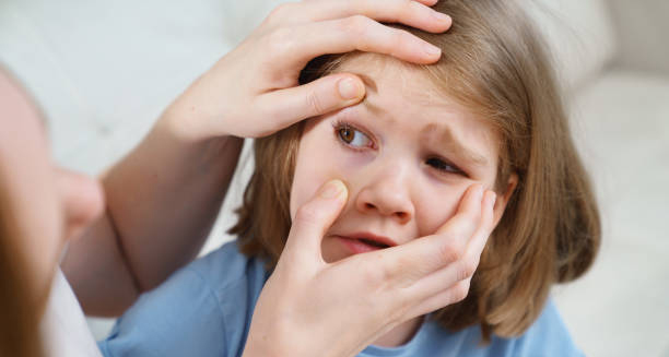 Adult examining young girl’s injured eye for signs of trauma
