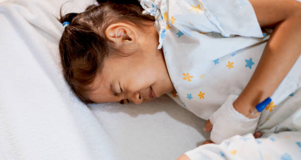 Child experiencing a febrile seizure while lying in a hospital bed