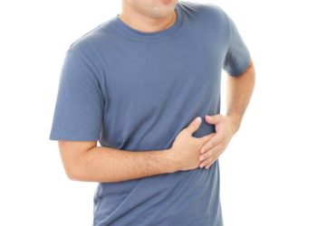 Man holding his side in discomfort, indicating pain that may be a symptom of a cracked rib.