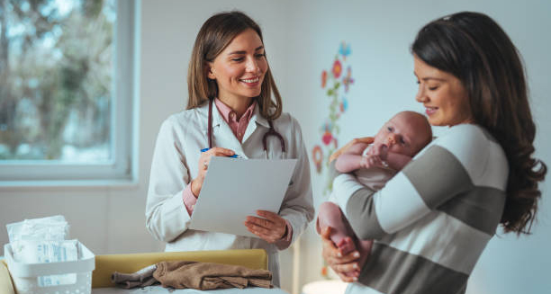 Smiling doctor speaking with a mother holding her baby