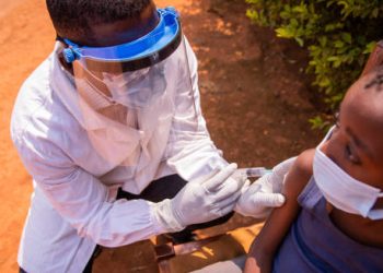 Healthcare worker administering cholera vaccine to a child wearing a face mask