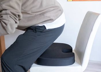 Man sitting on ergonomic cushion to relieve coccyx pain