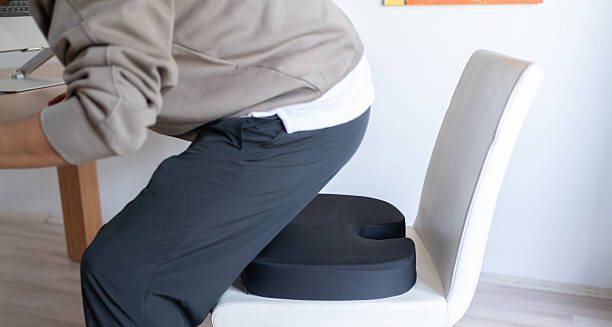 Man sitting on ergonomic cushion to relieve coccyx pain