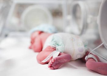 Newborn baby lying in an incubator with medical monitoring, representing early treatment for craniosynostosis.
