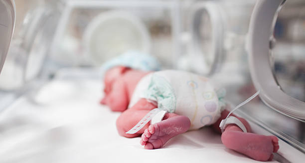 Newborn baby lying in an incubator with medical monitoring, representing early treatment for craniosynostosis.