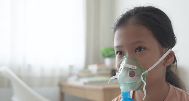 Young girl using a nebuliser mask at home, receiving respiratory treatment for croup.