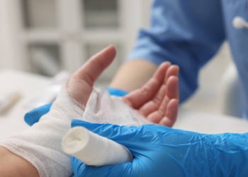 Medical professional applying a bandage to a hand wound.