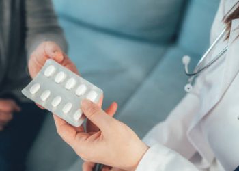 Doctor handing a blister pack of antiviral tablets to a patient