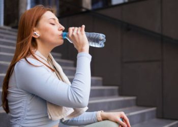 Woman drinking water from a bottle to rehydrate after exercise