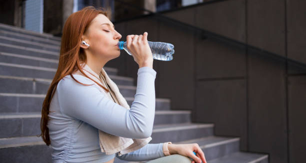 Woman drinking water from a bottle to rehydrate after exercise