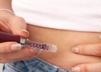 Person administering insulin injection into abdomen