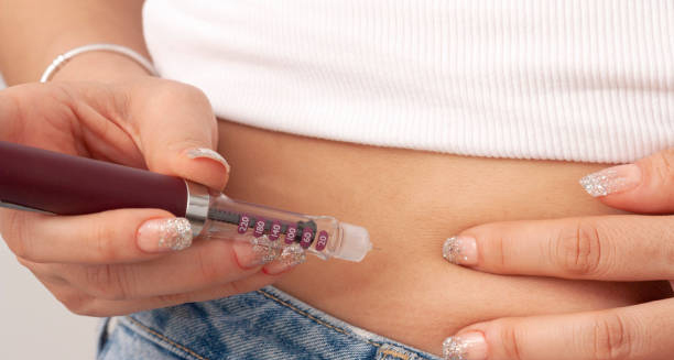 Person administering insulin injection into abdomen