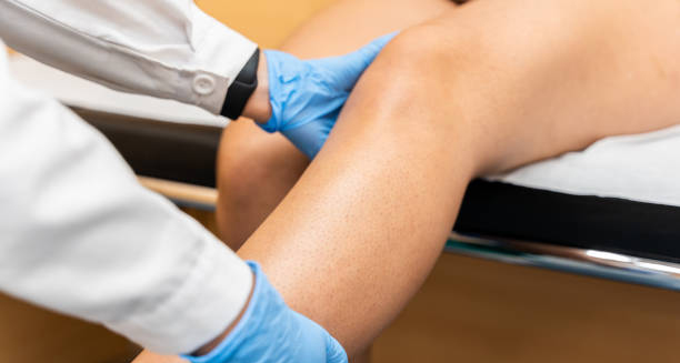 Doctor examining patient’s knee for dislocation treatment on clinic bed