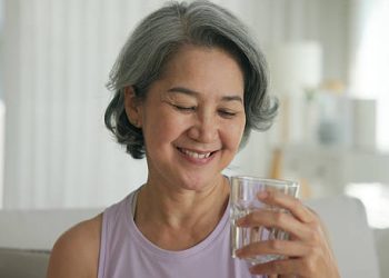 Older woman smiling while holding a glass of water