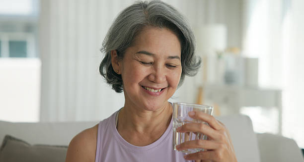 Older woman smiling while holding a glass of water